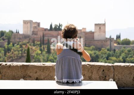 Kleines Mädchen macht Foto mit DSLR-Kamera auf die Alhambra von San Nicolas Aussichtspunkt in Albacin, Granada.. Kleines Mädchen macht Foto mit DSLR-Kamera zur Alhambra. Stockfoto