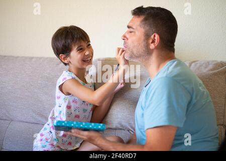 Kleine nette Tochter tun Make-up zu ihrem Vater. Papa verbringt Freizeit mit ihrer Tochter. Alternative Männlichkeit Konzept.. Kleine nette Tochter tun Make-up zu ihrem Vater Stockfoto