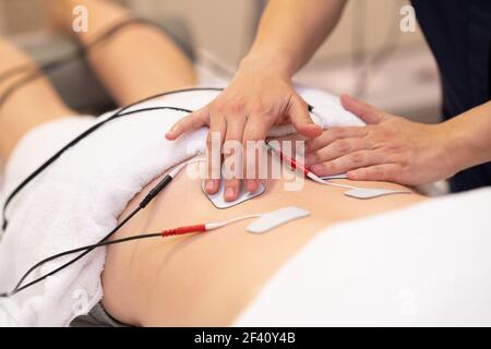 Physiotherapeut Anwendung Elektrostimulation in der Physiotherapie auf eine junge Frau.. Elektrostimulation in der Physiotherapie für eine junge Frau Stockfoto