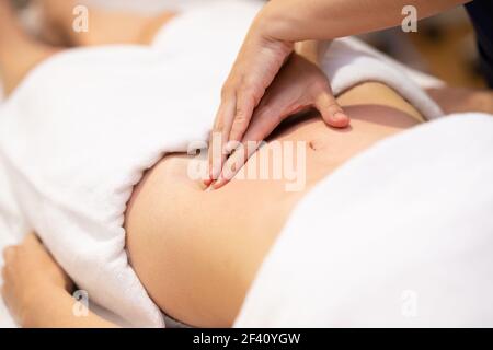 Frau, die eine Bauchmassage in einem Physiotherapiezentrum erhält. Weibliche Patientin wird von einem professionellen Osteopathie-Therapeuten behandelt. Frau, die eine Bauchmassage in einem Physiotherapiezentrum erhält. Stockfoto