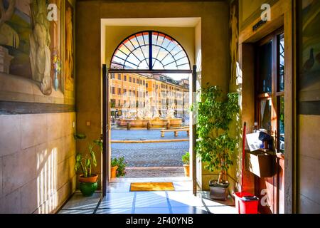 Blick auf den Neptun Brunnen mit Cafés hinter einer Tür eines mittelalterlichen Gebäudes auf der Piazza Navona in Rom, Italien Stockfoto