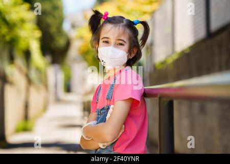 Happy Child Mädchen trägt eine Schutzmaske gegen Coronavirus während Covid-19 Pandemie. KN95 Maske.. Kindermädchen trägt eine Schutzmaske gegen Coronavirus während Covid-19 Pandemie Stockfoto