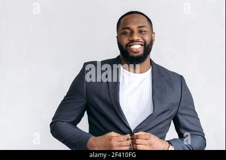 Porträt eines eleganten afroamerikanischen Geschäftsmannes in formellem Anzug. Erfolgreiche junge Erwachsene männliche Unternehmer im Büro stehen, Blick auf die Kamera, lächelnd Stockfoto