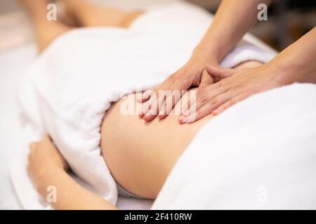 Frau, die eine Bauchmassage in einem Physiotherapiezentrum erhält. Weibliche Patientin wird von einem professionellen Osteopathie-Therapeuten behandelt. Frau, die eine Bauchmassage in einem Physiotherapiezentrum erhält. Stockfoto