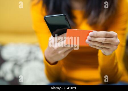 Perserin, die mit ihrem Smartphone online einkauft und mit ihrer Kreditkarte bezahlt. Frau, die mit dem Smartphone einkaufen und mit ihrer Kreditkarte bezahlen muss Stockfoto