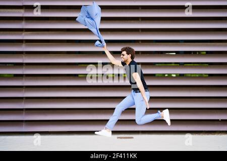 Lustige junge Mann trägt einen Anzug springen im Freien. Glücklicher Geschäftsmann im städtischen Hintergrund. Junger Mann in einem Anzug springen im Freien Stockfoto