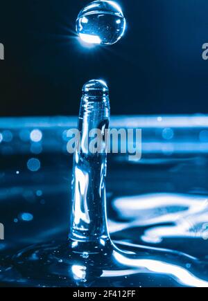 Farbiger Wassertropfen, kreisförmige Wellen, Wasserspritzer, Nahaufnahme. Stockfoto
