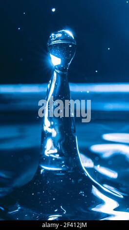 Farbiger Wassertropfen, kreisförmige Wellen, Wasserspritzer, Nahaufnahme. Stockfoto