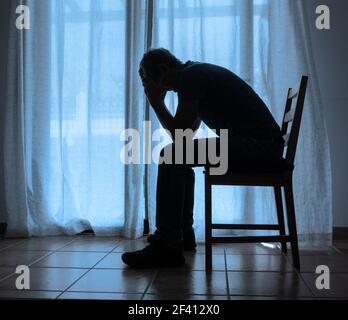 Reifer Mann (63 Jahre alt) mit Kopf in den Händen in der Nähe des Fensters. Männliche Depression, psychische Gesundheit, psychische Krankheit... Konzept Stockfoto