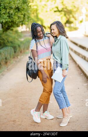 Zwei multiethnische Mädchen posiert zusammen mit bunten Freizeitkleidung im Freien.. Zwei multiethnische Mädchen posieren zusammen mit farbenfroher Freizeitkleidung Stockfoto