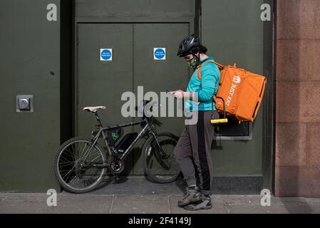 Essen Sie einfach einen Radfahrer, der sein Telefon auf der Princes Street, Edinburgh, Schottland, Großbritannien überprüft. Stockfoto
