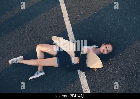 Sehr müde Skater Mädchen schlafen auf Asphalt in warmen Sommertag, Copyspace. Müde Skater Mädchen schlafen auf Asphalt in warmen Sommertag Stockfoto