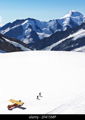Schweiz Jungfraujoch-Top of Europe. Flugzeug auf Gletscher mit Bergen im Hintergrund und zwei Personen zu Fuß entfernt. Der Große Aletschgletscher, Stockfoto