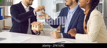 Makler geben Schlüssel aus dem neuen Haus zu interracial paar in Office-Aufnahme Stockfoto