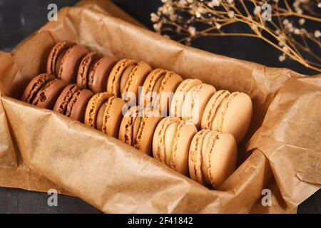 Natürlich braune, beige und cremefarbene französische Macarons mit Kaffee-, Mokka-, Schokolade- und Vanillegeschmack im Blech mit Backpapier Stockfoto