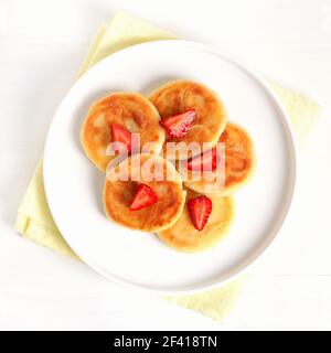 Quark Pfannkuchen mit Erdbeere, syrniki auf weißem Teller. Draufsicht, flach liegend Stockfoto