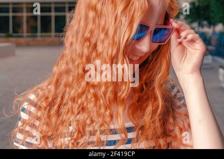 Ingwer behaarte Mädchen berühren lustige Sonnenbrille und Blick weg und nach unten. Ingwer behaarte Mädchen in lustige Sonnenbrille suchen weg und nach unten Stockfoto