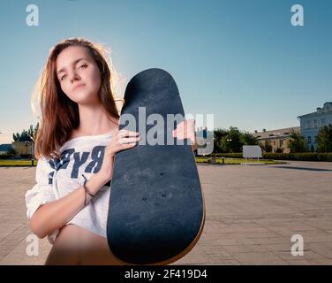 Weitwinkel-Aufnahme von Skater Mädchen mit Skateboard auf ihrem shouler, viel Platz für Text am Himmel. Weitwinkel Aufnahme von Skater Mädchen mit Skateboard auf ihrem shouler Stockfoto