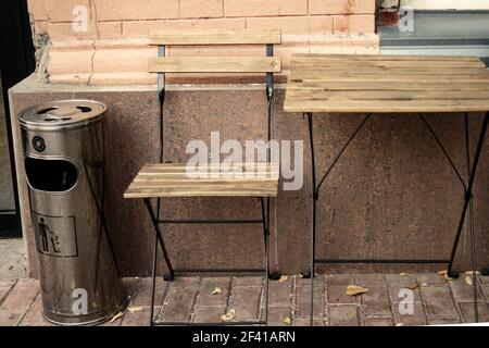 Holztisch und Stuhl draußen Cafe mit Mülleimer in der Nähe. Holztisch und Stuhl draußen Cafe mit Mülleimer Stockfoto