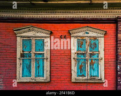 Geschlossene hölzerne Fensterläden an den Fenstern in den roten Ziegelsteinen Wand des Hauses Stockfoto