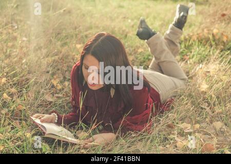 Retro Mädchen im Gras liegen und Buch lesen, Copyspace Stockfoto