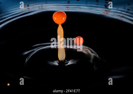 Farbiger Wassertropfen, kreisförmige Wellen, Wasserspritzer, Nahaufnahme. Stockfoto