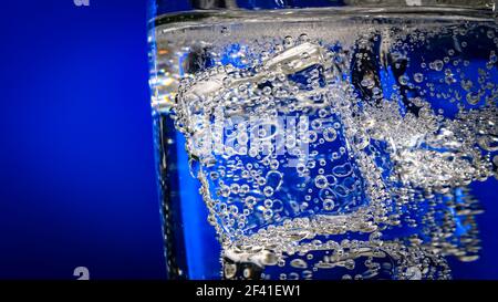 Glas Wasser mit Eis auf einem dunkelblauen Hintergrund Stockfoto