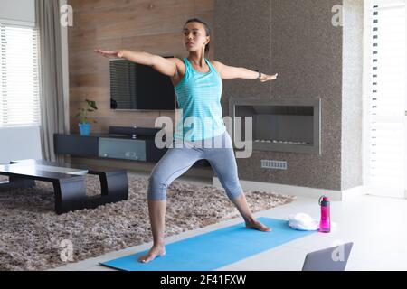afroamerikanische Frau, die Yoga vor dem Laptop praktiziert Zu Hause Stockfoto