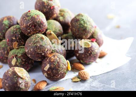 Rohe Energiekugeln mit Matcha-Teepulver auf grauem Hintergrund. Rohe vegane, vegetarische Süßigkeiten. Zuckerfrei, glutenfrei, laktosefrei Stockfoto