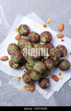 Rohe Energiekugeln mit Matcha-Teepulver auf grauem Hintergrund. Rohe vegane, vegetarische Süßigkeiten. Zuckerfrei, glutenfrei, laktosefrei Stockfoto