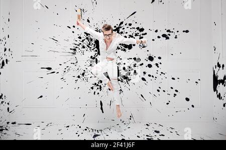 Hübscher junge Maler plantschen mit schwarzer Farbe Stockfoto