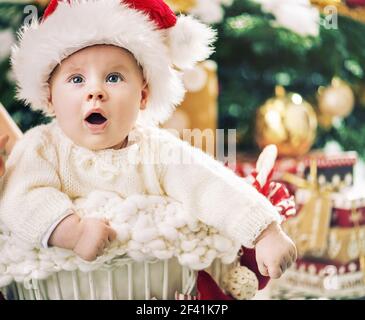 Charmante kleine Santa junge mit einem Weihnachtsbaum im Hintergrund Stockfoto