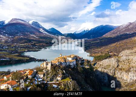 Drohnenfoto einer kleinen antiken Stadt in den Abruzzen auf einem Hügel an einem See mit wunderbarem bergblick. Stockfoto