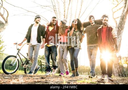 Gruppe von städtischen Freunden Gang zu Fuß in der Stadt Skatepark Mit Hintergrundbeleuchtung bei Sonnenuntergang - Jugend und Freundschaft Konzept mit Multirassische junge Menschen Stockfoto