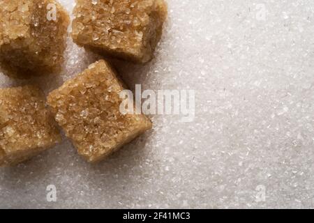 Weiße, raffinierte Zuckergranulate und braune Zuckerwürfel aus nächster Nähe. Hintergrund für das Essen. Stockfoto