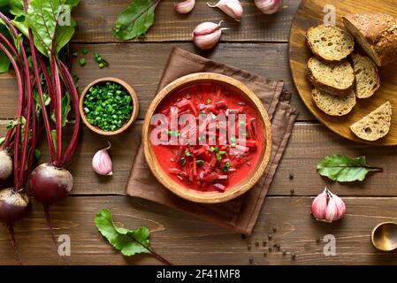 Leckere Rote Beete Suppe mit saurer Sahne und Grüns in Schüssel, Borscht auf Holzhintergrund. Draufsicht, flach liegend Stockfoto