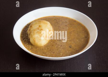 Ein Teller Linsen mit Kartoffeln auf einem Holztisch. Hülsenfrüchte und hausgemachte Speisen Rezepte. Stockfoto