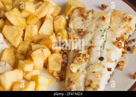 Seehechtfilet mit Knoblauch serviert mit pommes frites in Quadrate auf einem Küchenteller geschnitten. Vegetarische Rezepte. Stockfoto