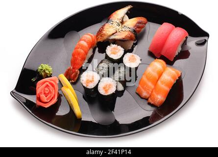 Schwarzer Teller mit verschiedenen Sushi-Sorten auf weißem Hintergrund. Draufsicht. Stockfoto