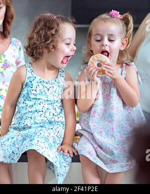 Süße Kinder essen süße, bunte Donuts Stockfoto