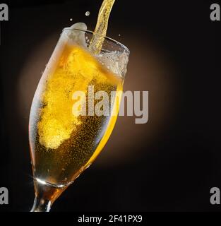 Der Bierstrahl wird in ein Bierglas gegossen, wodurch viele Blasen und Schaum entstehen. Dunkelbrauner Hintergrund. Stockfoto