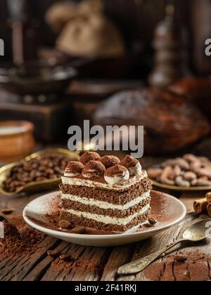 Scheibe Schokoladenkuchen mit Tiramisu-Sahne und Kakaopulver auf Holztisch. Stockfoto