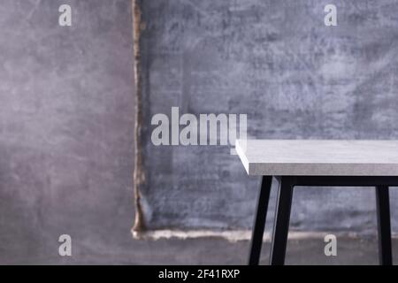 Tisch oder Metall Hocker und abstrakt bemalte Leinwand in der Nähe Betonwand Hintergrund. Tischplatte oder Ablage Stockfoto