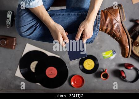 Männliche Hände halten Pass oder Notebook und Bein in Jeans mit alten Reisen Lederstiefel Schuhe. Mann und entspannen oder Kunst Musik Lebensstil Konzept Stockfoto
