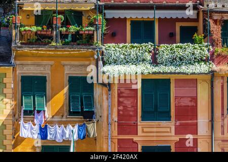 Fassade eines Gebäudes mit Balkonen voller Blumen und hängender Kleidung. Historischer italienischer Palast. Stockfoto