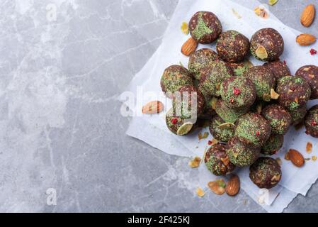 Rohe Energiekugeln mit Matcha-Teepulver auf grauem Hintergrund. Rohe vegane, vegetarische Süßigkeiten. Zuckerfrei, glutenfrei, laktosefrei Stockfoto