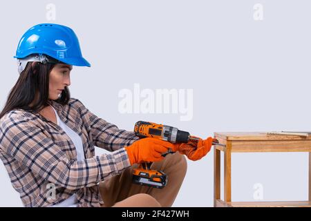 Zimmermannin bohrt mit einem elektrischen Bohrer ein Loch. Reparatur- und Renovierungskonzept. Frau reparieren Werkzeuge für Hausbauer. Akku-Bohrmaschine Stockfoto