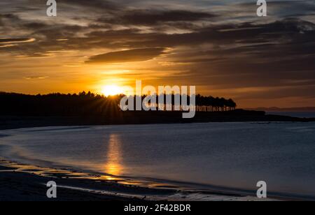East Lothian, Schottland, Großbritannien, 18th. März 2021. UK Wetter: Atemberaubender Sonnenuntergang am Yellowcraig Strand. Ein herrlicher sonniger Tag endet mit einem farbenfrohen Sonnenuntergang über dem Firth of Forth und der geschwungenen Bucht Stockfoto