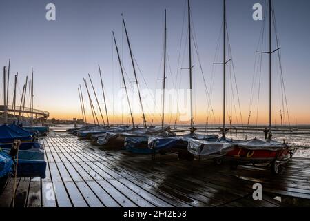 SOUTHEND-ON-SEA, ESSEX, Großbritannien - 24. OKTOBER 2010: Blick auf Jollen auf einem nassen Holzsteg bei Chalkwell bei Sonnenaufgang Stockfoto