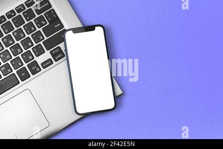 Business- und Finanzmockup mit modernem Smartphone auf Laptop, Schreibtisch und Arbeitsplatzfoto Stockfoto